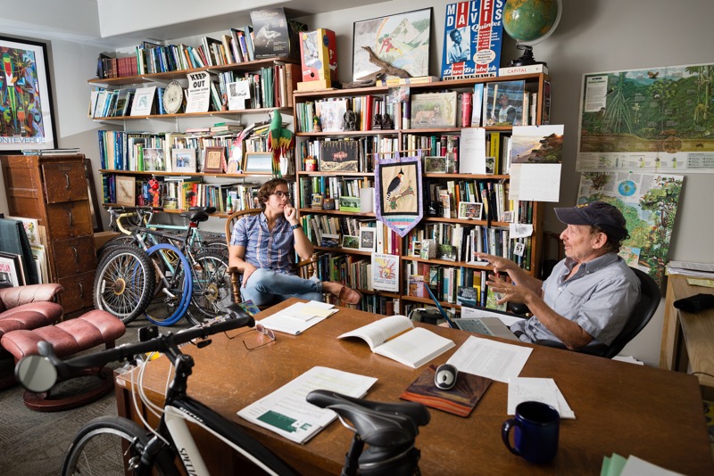 Professor and student meet in the professors cluttered, but homey, office to discuss a project.