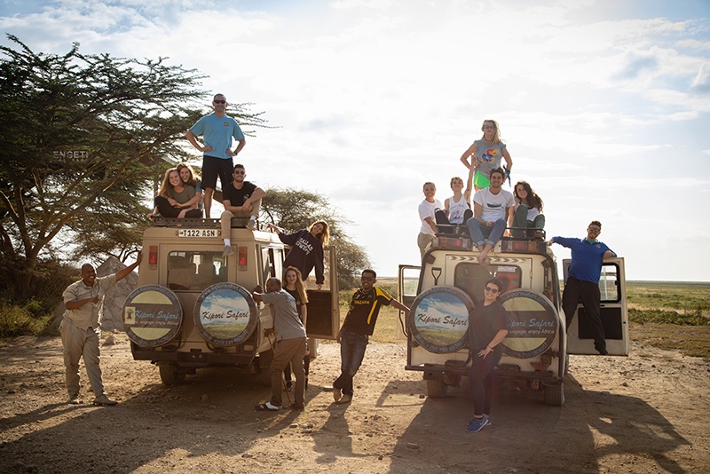 A dozen students pose on a pair of jeeps in Serengeti National Park.