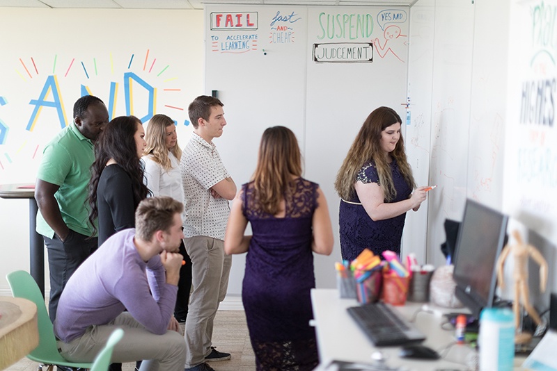 A group of students brainstorm at a white board.