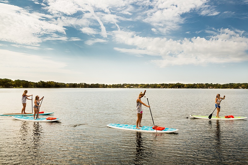 Four female college students paddle board on a Florida lake.